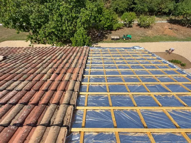 Toiture en tuiles anciennes à côté d’un pan préparé avec écran et liteaux neufs, avant rénovation